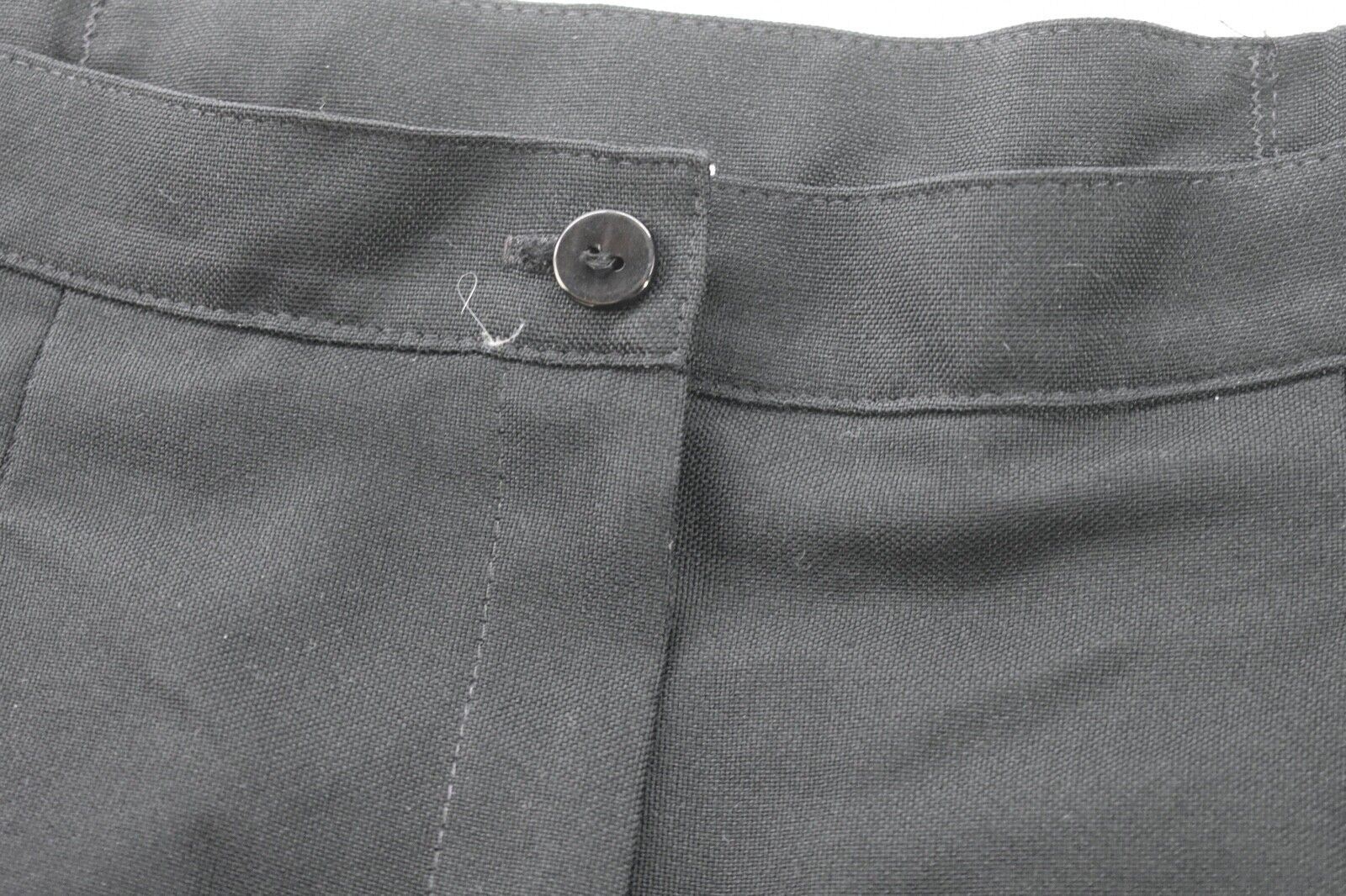 Black Jantzen women’s pants with front button closure, pleated detailing, and two front slash pockets on a dark fabric background.