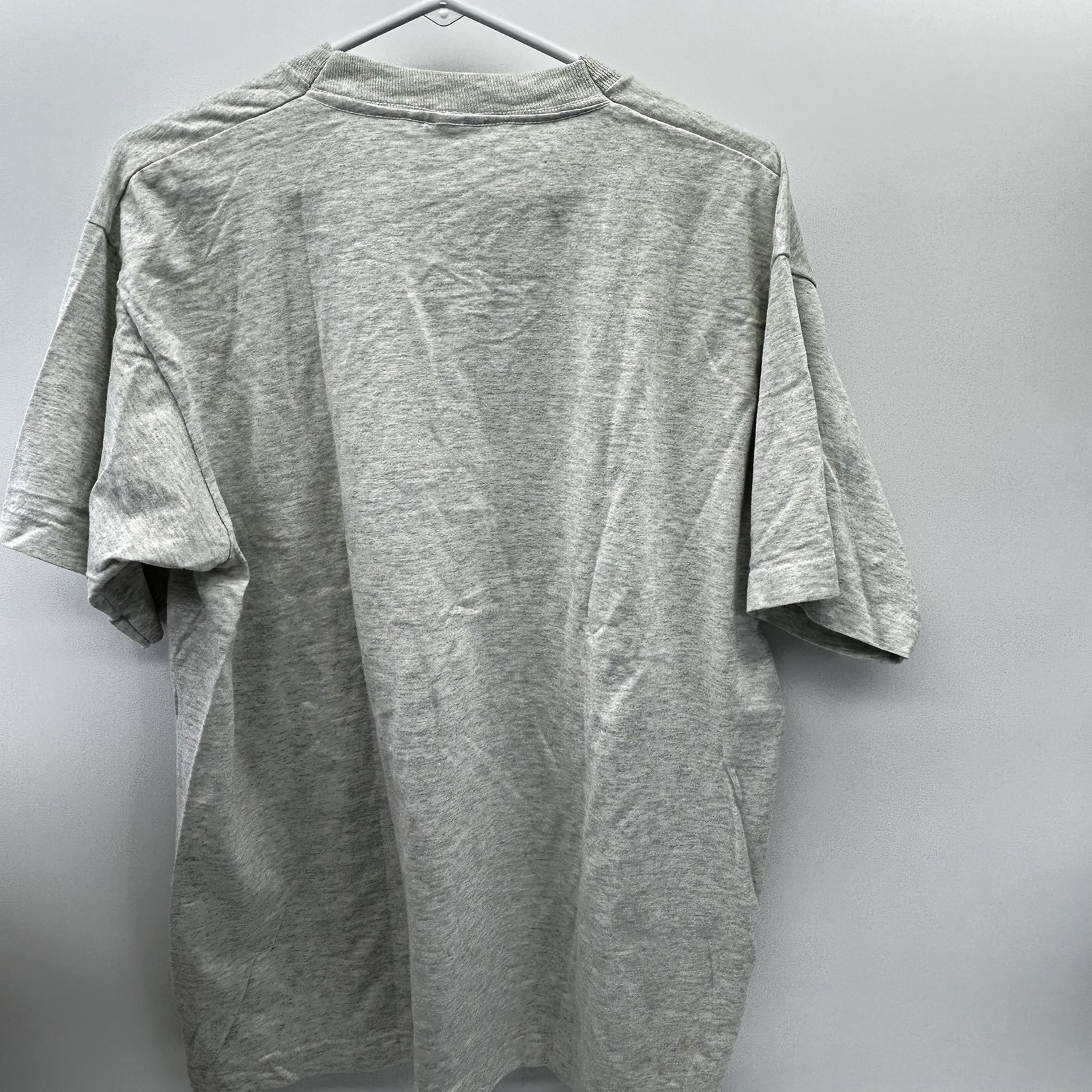 Gray vintage John Jay baseball T-shirt with short sleeves, shown from the back on a hanger against a white wall.