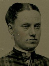 WOMAN HARSHLY PULLED BACK HAIR, PLAID DRESS. TINTED TINTYPE IN PERIOD PAPER MAT.