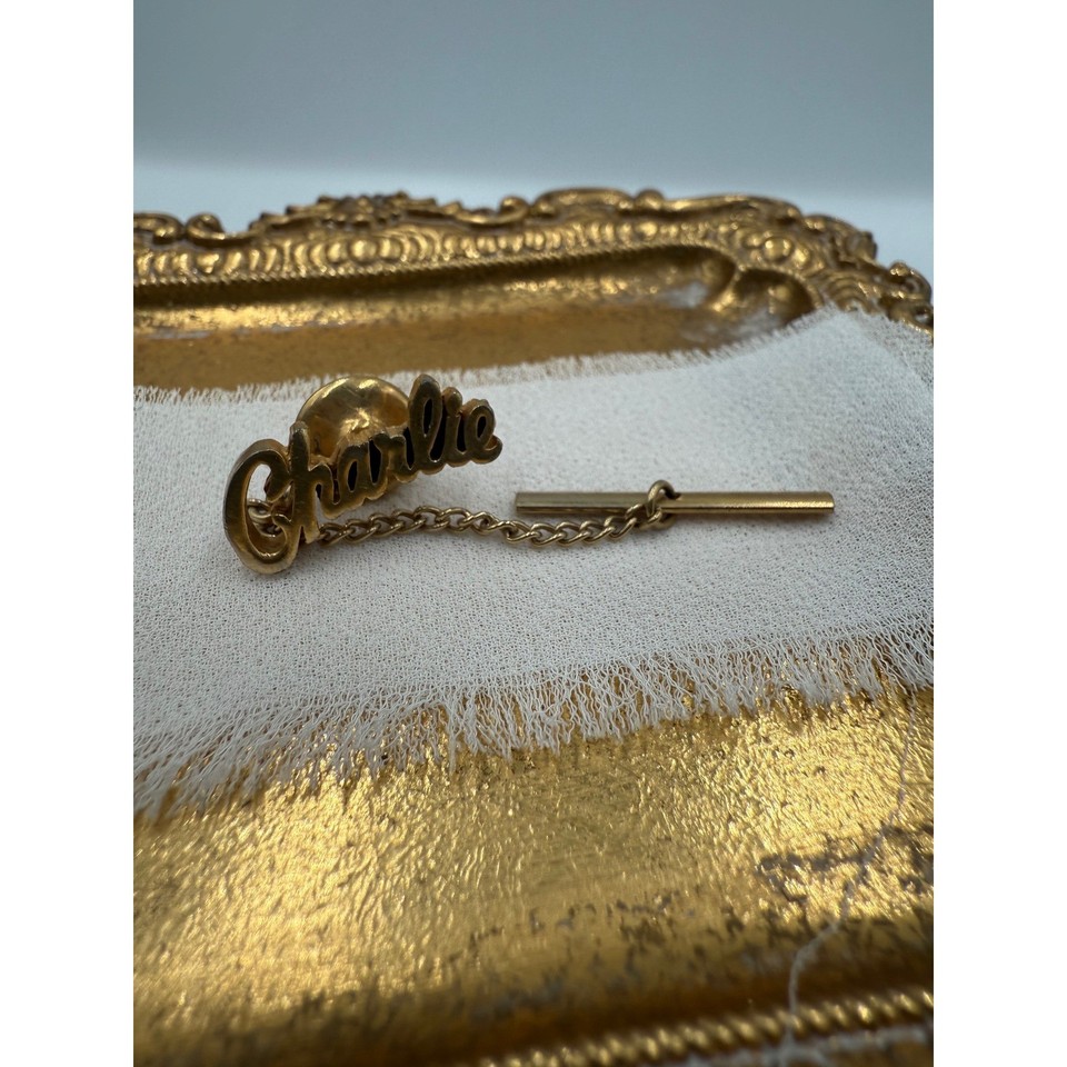 A vintage gold-tone script 'Charlie' tie tack — charmingly personal, the kind of old-school monogrammed accessory you'd find in a gentleman's jewelry box circa 1965.