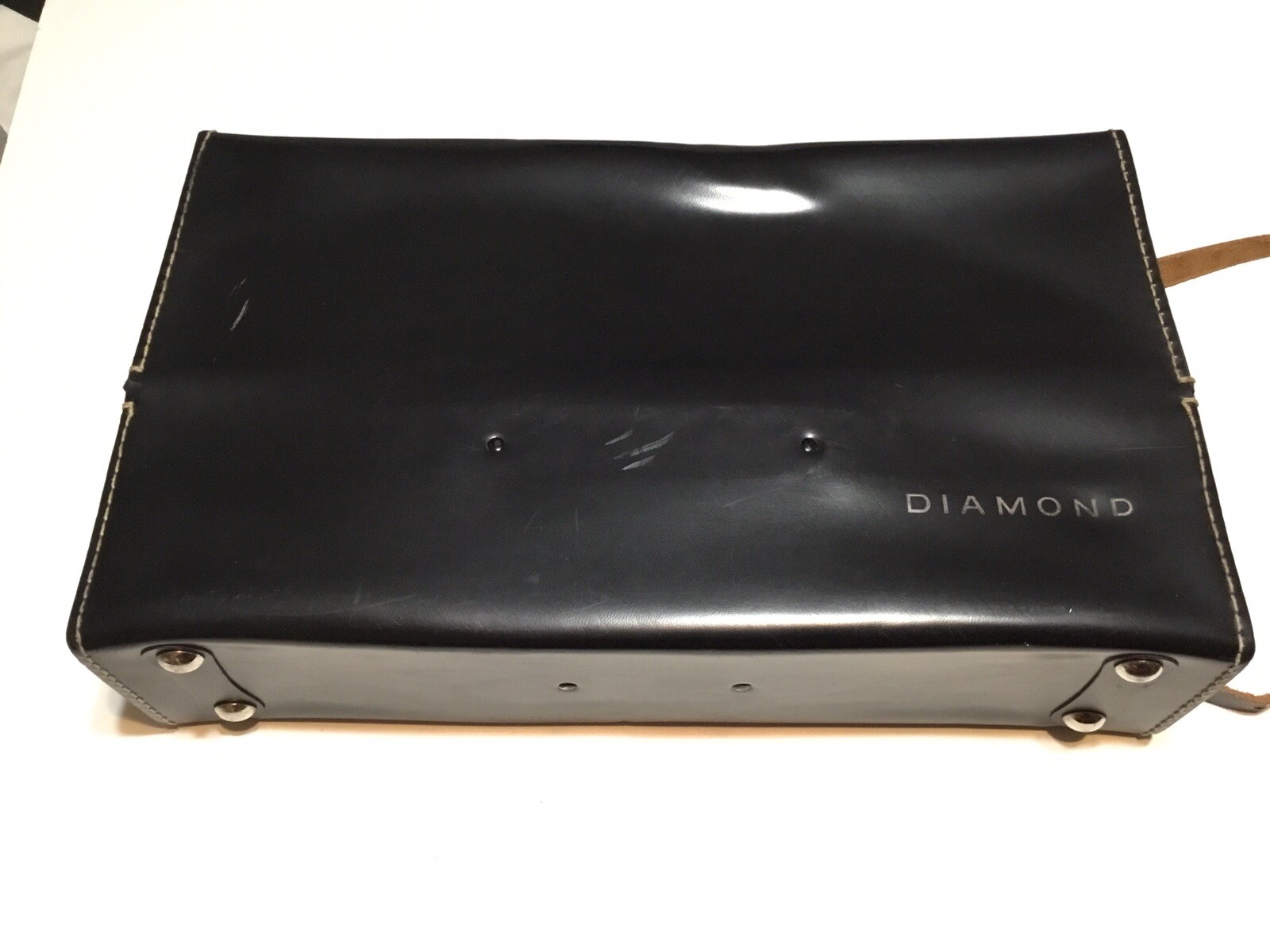 Black vintage hard camera case with dual handles, gold-tone stitching, and “Diamond” logo on textured leather surface.