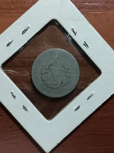 1910 Liberty Head V nickel with worn details, surrounded by white cardboard frame with metal rivets.