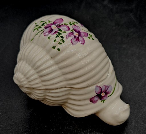 A charming figural ceramic snail trinket box with a smiling face and hand-painted violet flowers — the kind of delightful vintage oddity that looks great on a vanity or shelf.