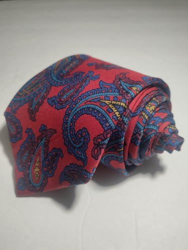 Red ETRO silk tie with yellow paisley pattern, blue and pink floral accents, and “Made in USA” label on white surface.