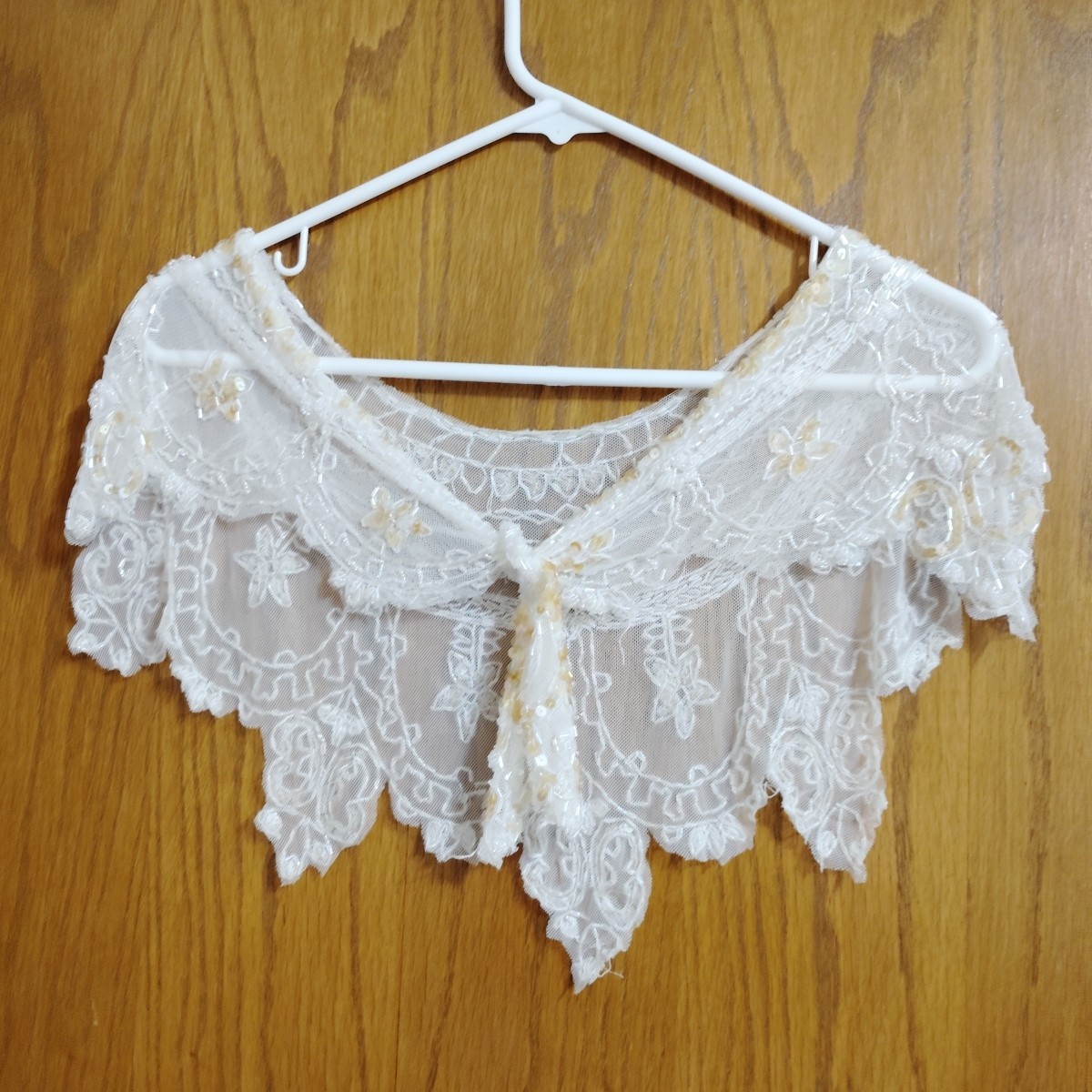Cream lace shawl with beaded trim draped flat.