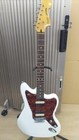White SQUIER VATAGE MOD JAGER electric guitar with gold hardware, brown fretboard, and black pickguard against ribbed background.