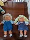 A pair of vintage Cabbage Patch Kids dolls, featuring distinctive soft bodies.