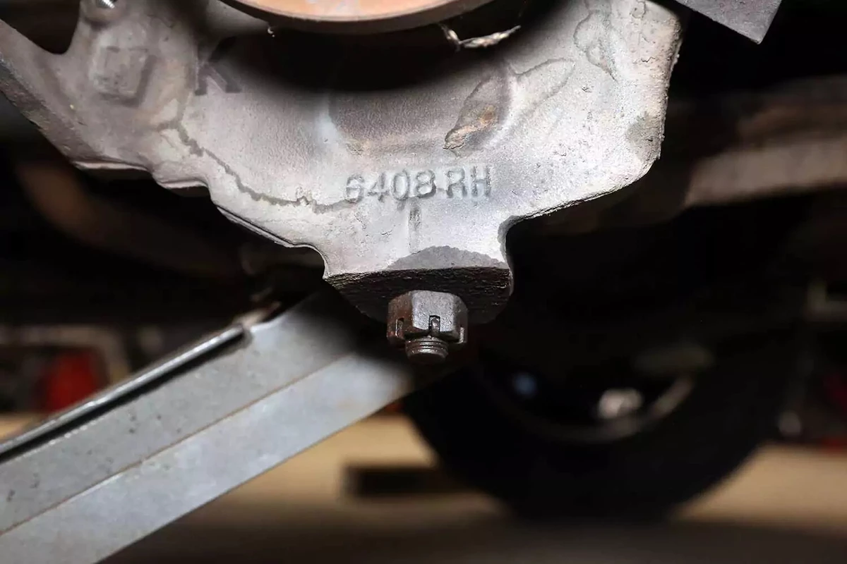 A lower ball joint castle nut lubricated with penetrating fluid, its cotter pin removed.