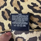 Brown leopard print fabric roll with yellow tag showing care label, laundry instructions, and “RL-7R” text.