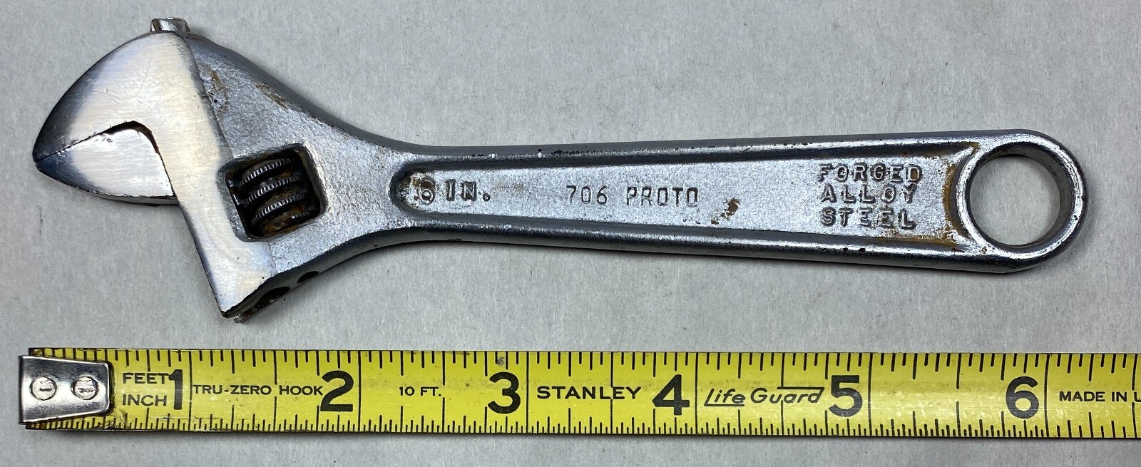 Chrome 6" adjustable crescent wrench with black handle, marked “706 PROTO FORGED ALLOY STEEL,” on white surface.
