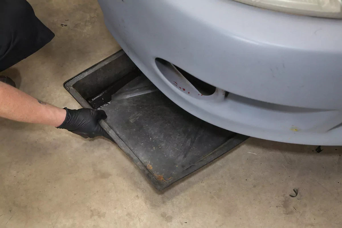 Sliding a drain pan underneath the vehicle.