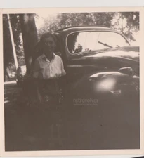 Charming Young Girl Poses Gracefully Beside Vintage Car in the Cool Shade Photo