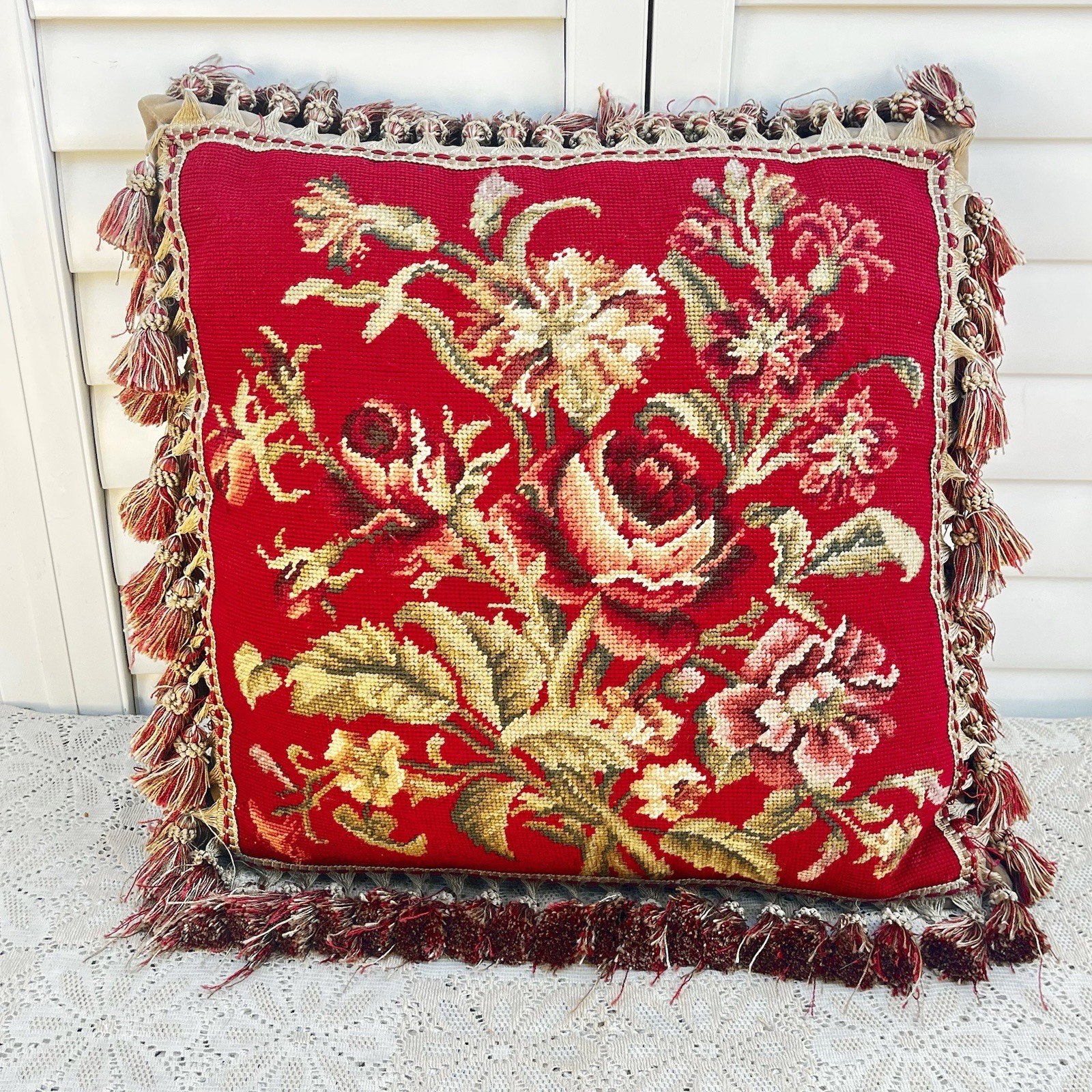 Large square needlepoint pillow with red rose bouquet design and tasseled fringe trim.