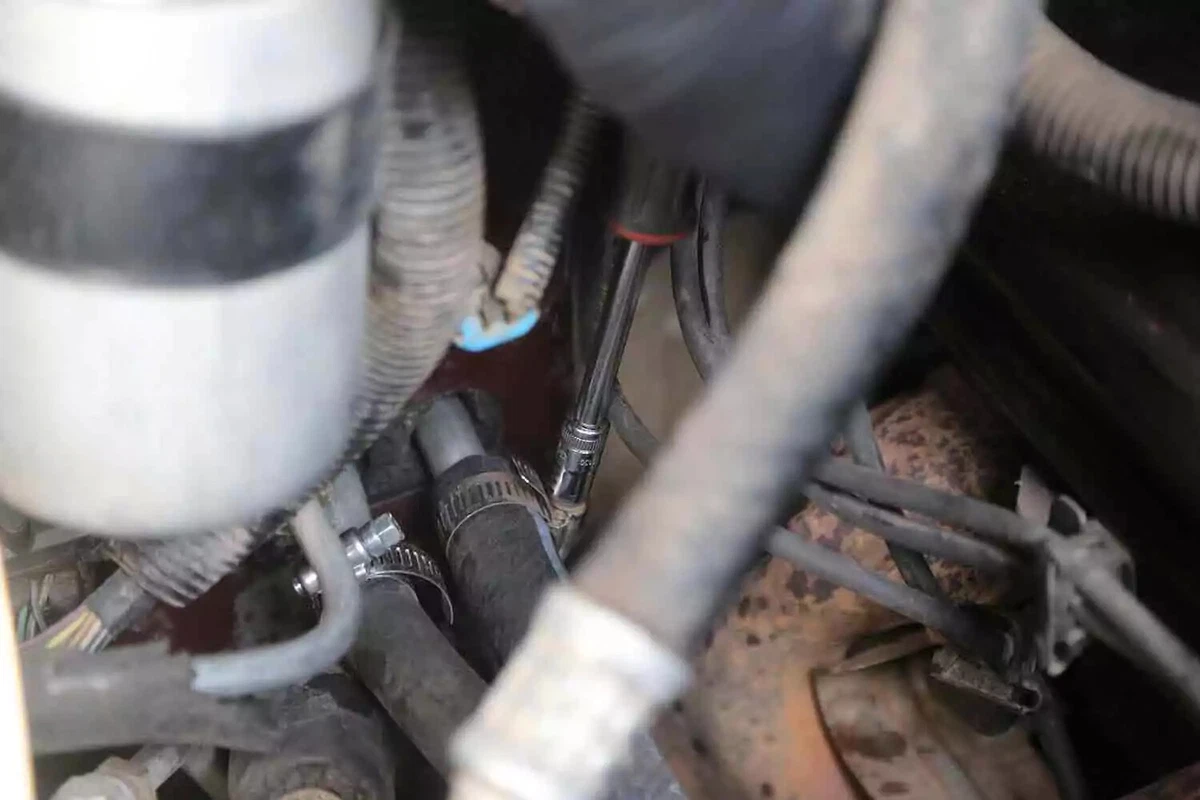 A screwdriver is used to tighten the hose clamps on the new heater core hoses.