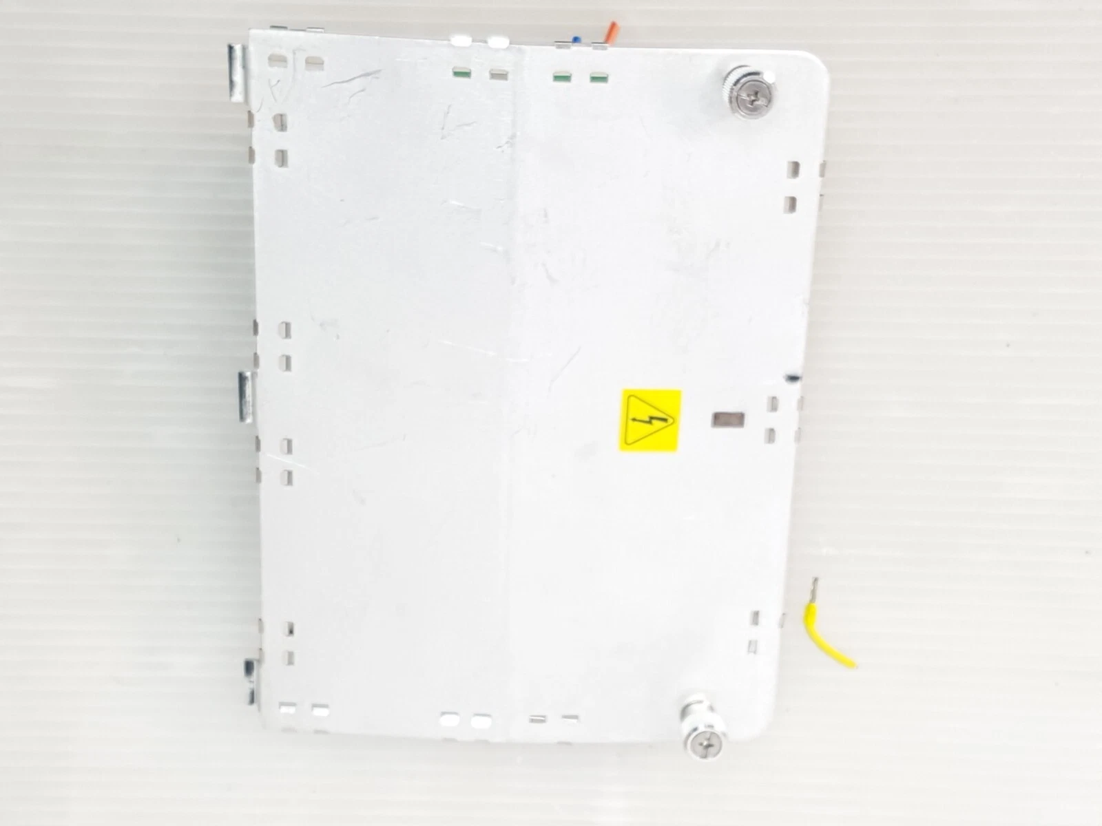 Top view of the aluminium plate with high-voltage warning label and captive thumbscrews