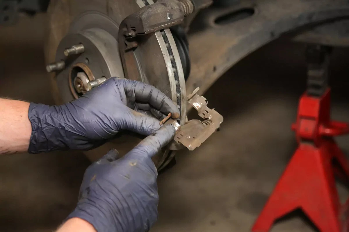Hand holding a brake pad spring clip.