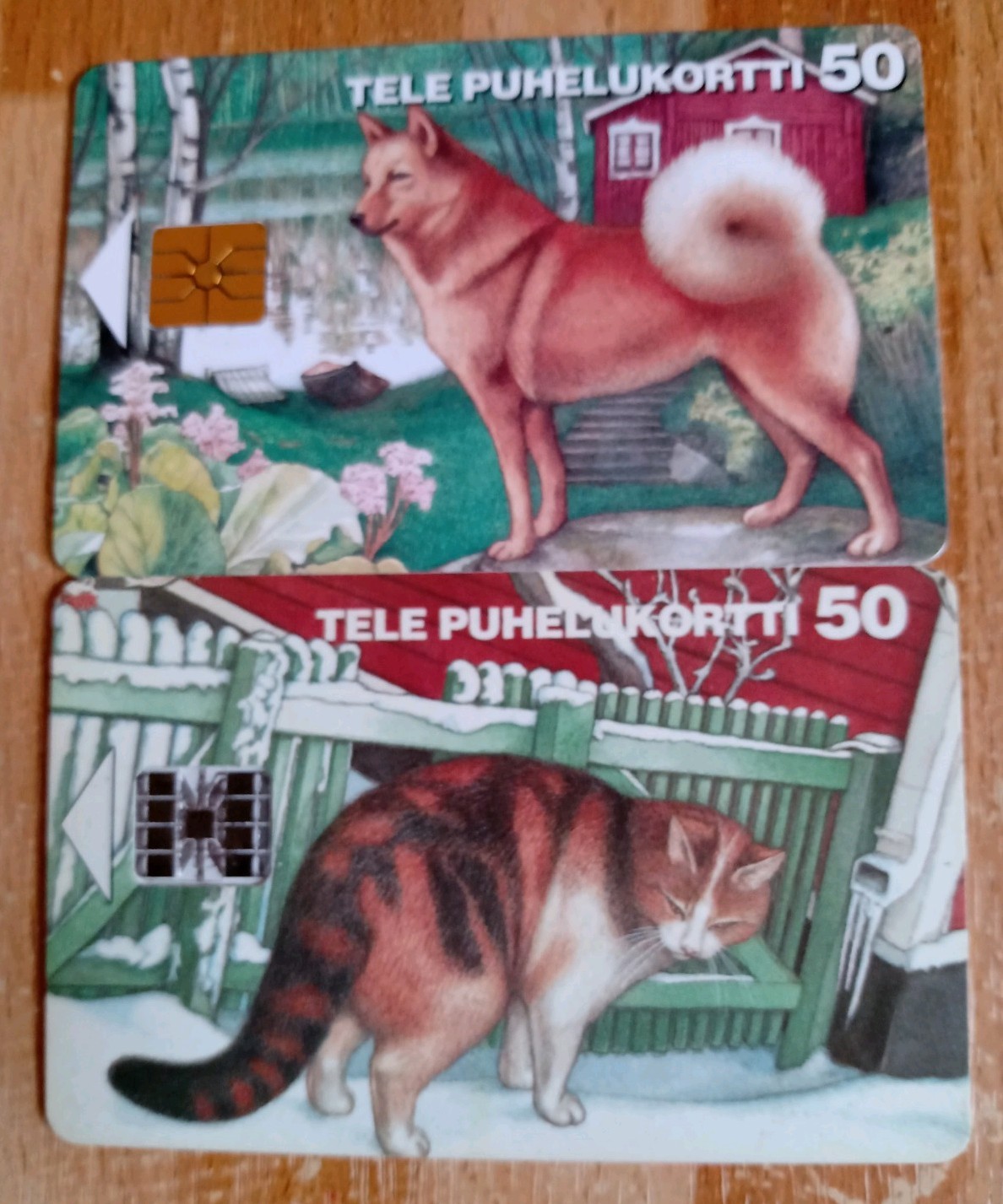 2 Phonecards Of Finland. A Dog In The Landscape. A Cat In The Snow By The Fence.