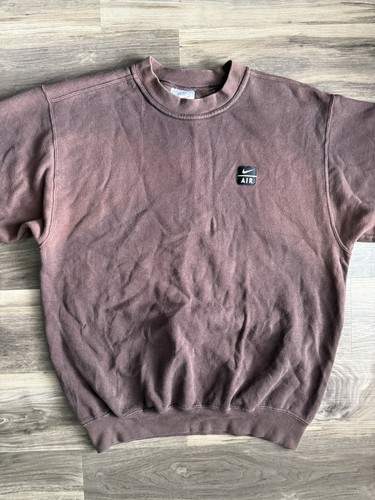 Brown vintage Nike sweatshirt with white swoosh logo, small square air unit, and visible yellow stitching.