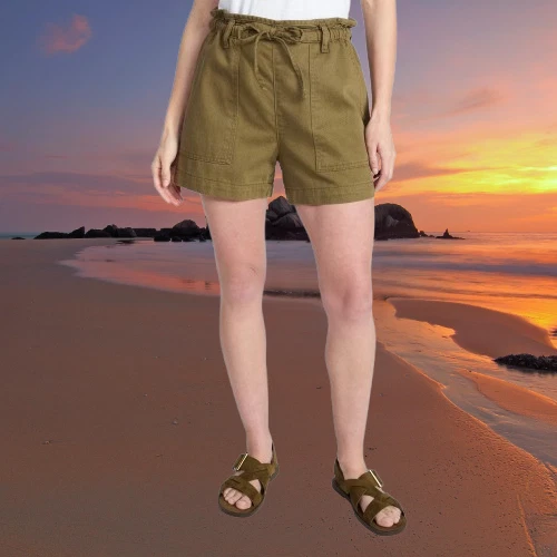Women's olive green twill utility shorts with front drawstring, side pockets, and ankle strap sandals on beach at sunset.