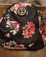 Black Mini Backpack With A Floral Design And Crisscross Pattern Zipper Closure.