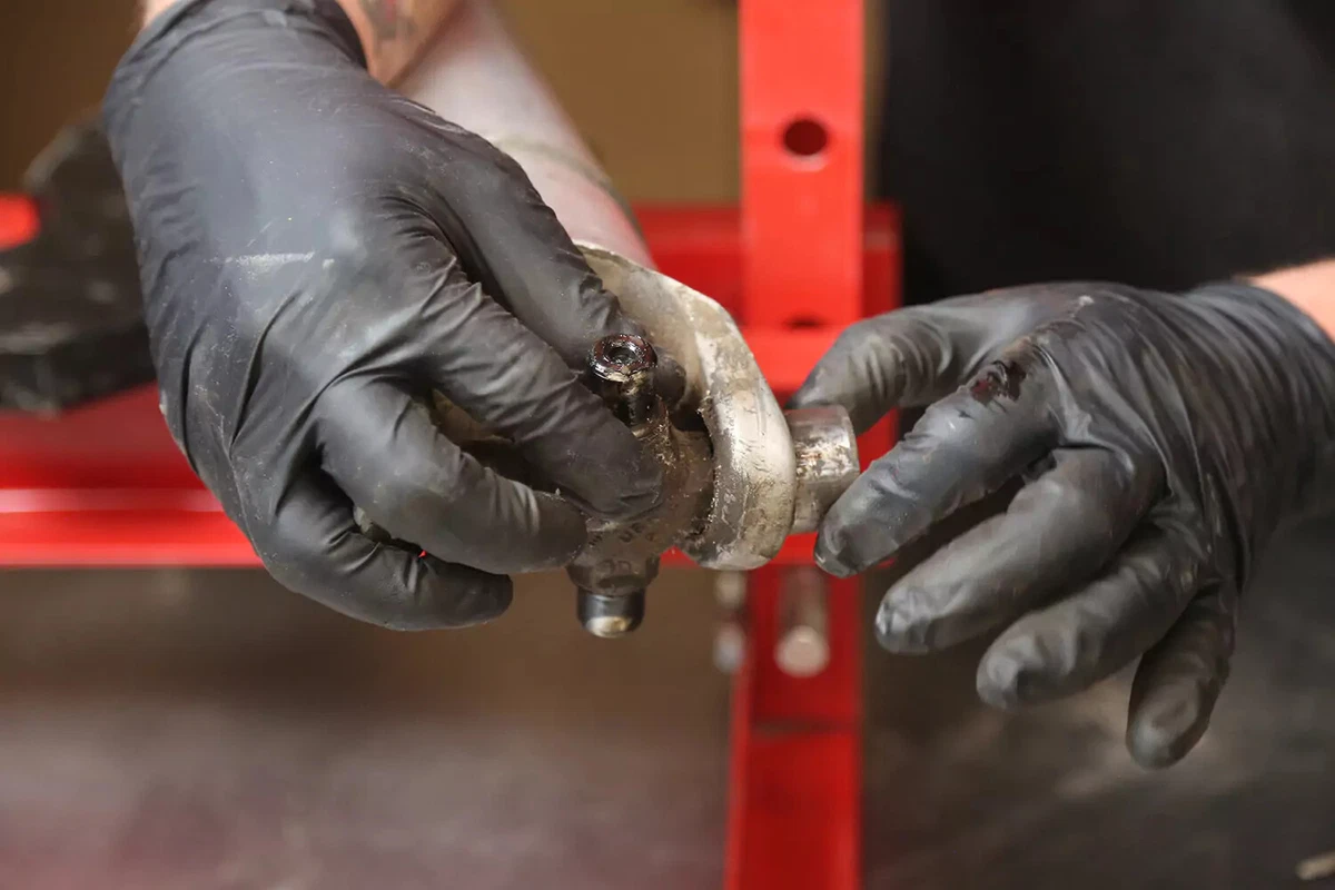 A mechanic wearing black gloves removes the cap from the welded yoke.