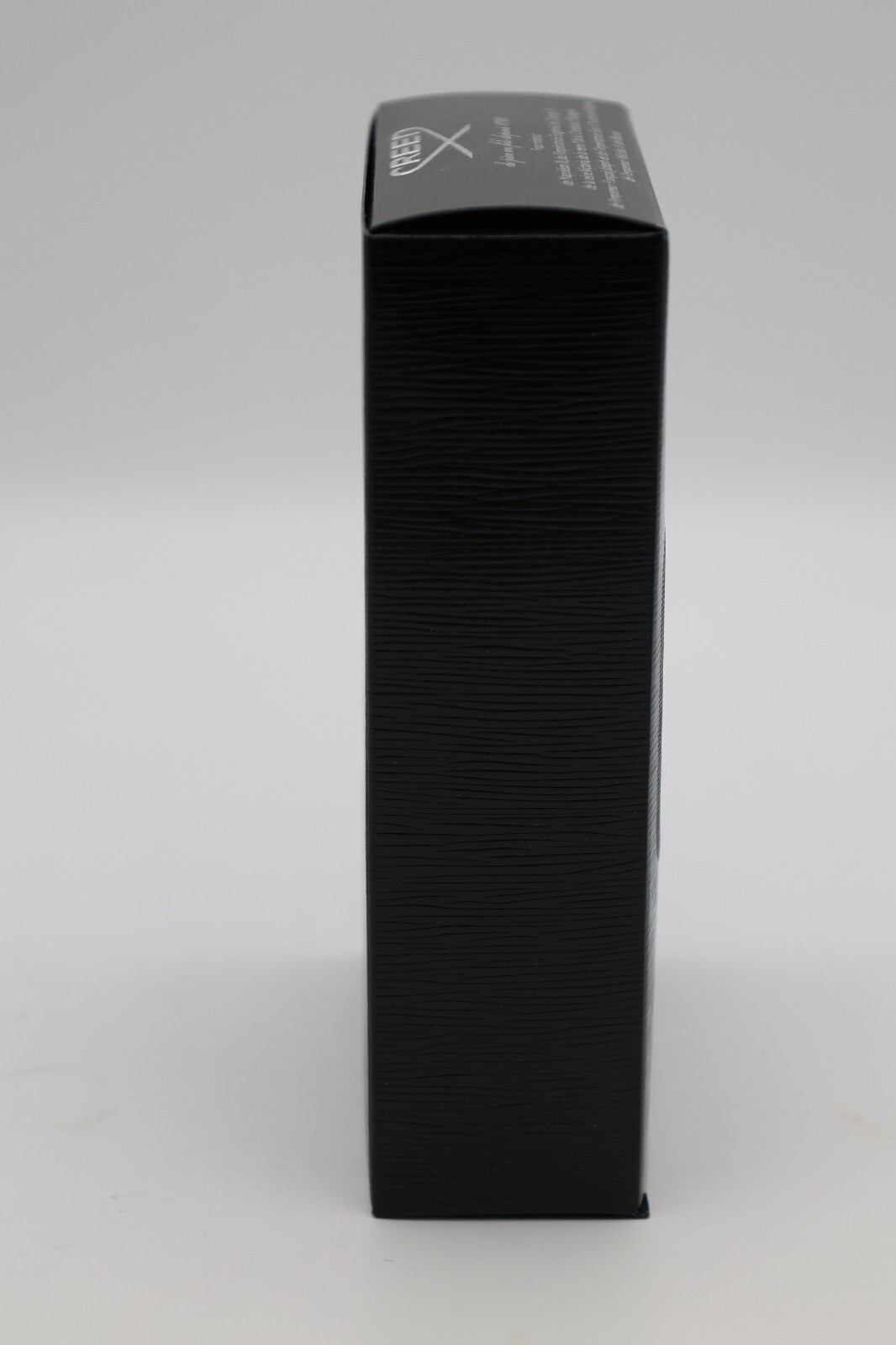 Black rectangular box with subtle horizontal texture, featuring white “CREED” logo and cross symbol on the top side.