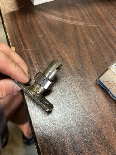 Metallic 1964-1966 Ford truck distributor cam with brass shaft and black side handle, worn by age and use.