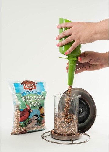 Hand holding green plastic jar of Farmer’s Delight Wild Bird Food with cherry flavor, birds in background, 10-pound bag.