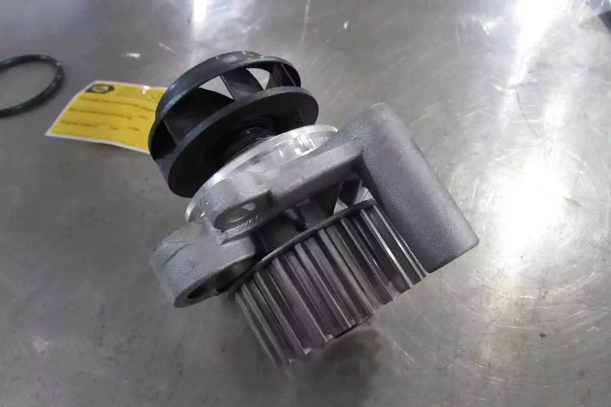 : A top view of a timing belt-driven water pump, displayed on a metal work surface.