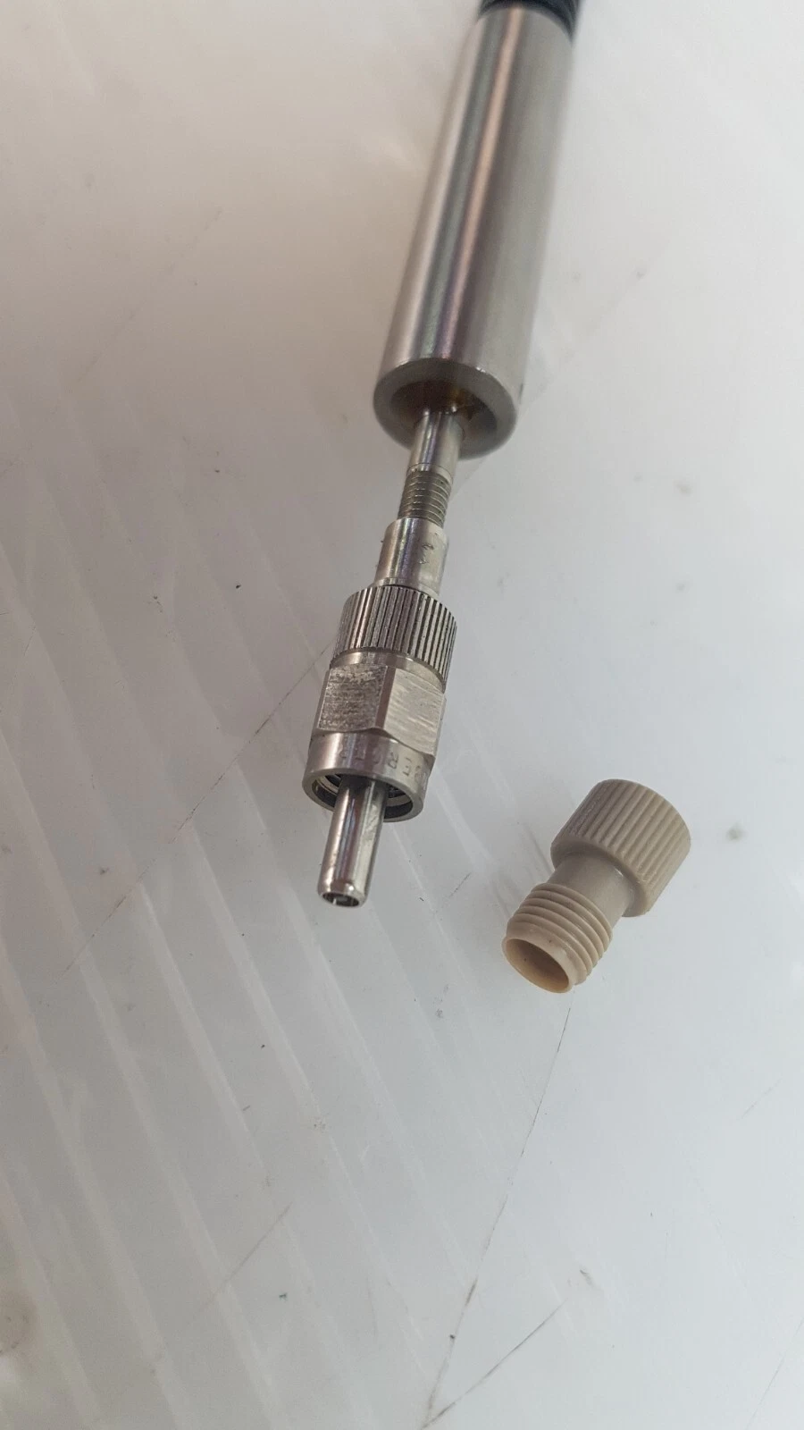 Close-up of the fiber connector ferrule next to its screw-on dust cap
