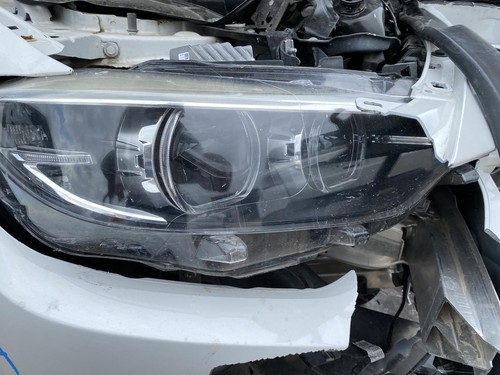 Black BMW 430I headlight with clear lens, side impact damage, and visible wiring.