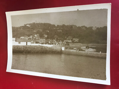 Eine unbekannte Strandpromenade.  Boote im Meer & Stadt dahinter.   Alte Postkarte.  0