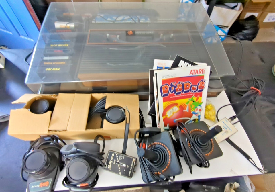 An Atari 2600 housed in a dedicated cabinet case with a game lot is a self-contained retro arcade setup — this is a display piece AND a party conversation starter.