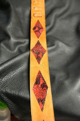 Black leather guitar strap with red diamond inlay featuring small black snakeskin pattern, made in USA.