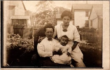 Postcard Real Photo RPPC Unhappy Woman Sitting in Wicker Chair Holding Baby