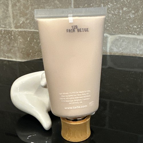 White tube of Tarte Amazonian Clay 16-Hour Full Coverage Foundation with gold cap, displayed on a white ceramic sink.