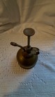 Vintage brass hand pump oiler with curved handle and long pump nozzle, made in USA on textured white fabric background.
