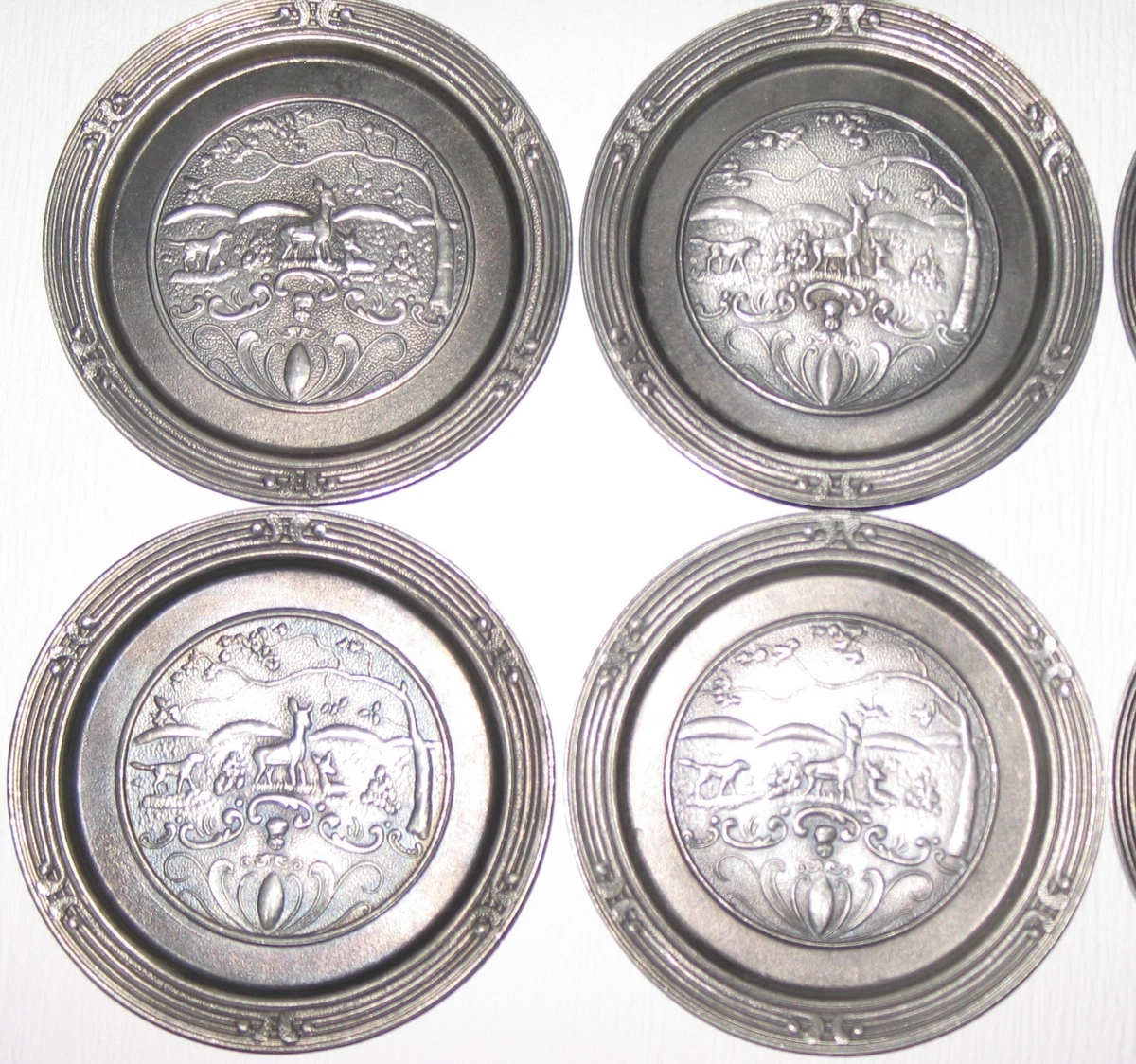Neunteiliges Zinn-Untersetzer-Set mit detaillierten Relief-Jagdmotiven (Rehe, Ja
