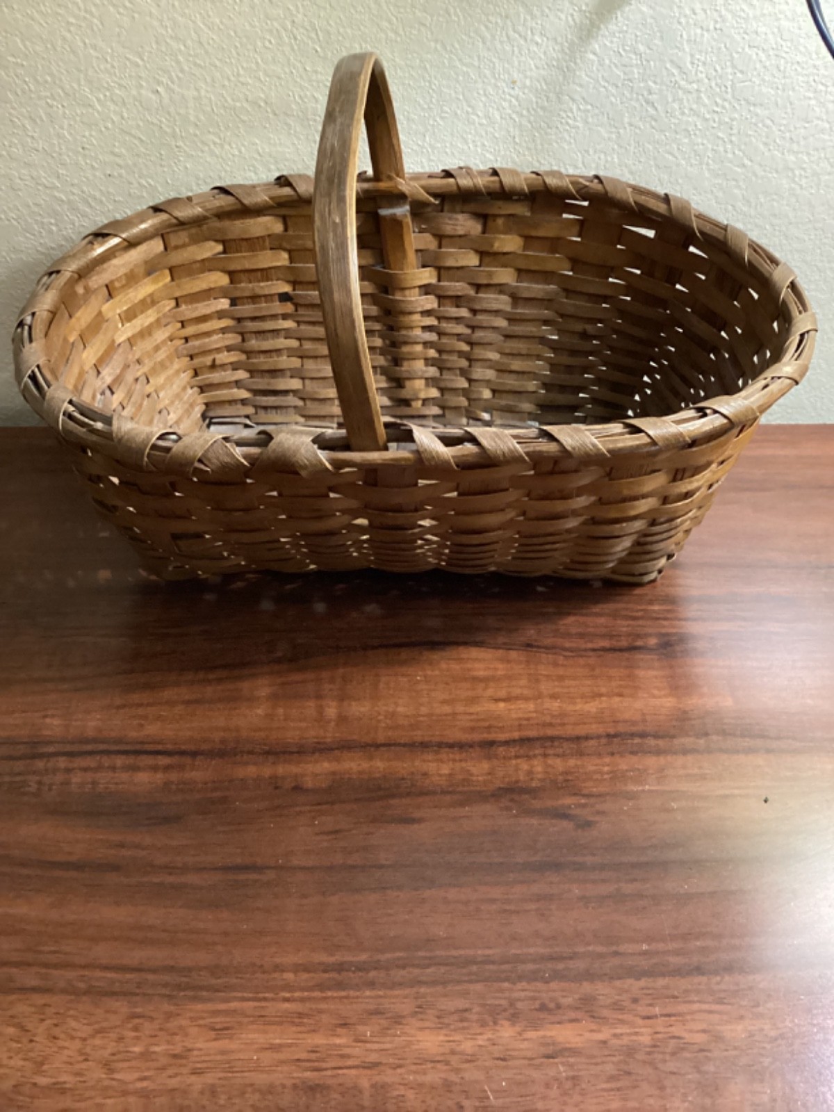 Antique oak splint market basket with a woven handle and worn patina, shown on a white background.