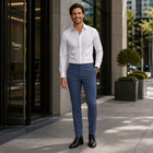 Theory men’s dress pants in blue slim-fit with black shoes, white shirt, standing outdoors near a tall building.
