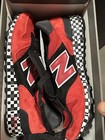 Red and black New Balance 1300 sneakers size 9 with white laces, gray accents, and black checkered sole in a red shoebox.