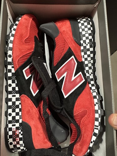 Red and black New Balance 1300 sneakers size 9 with white laces, gray accents, and black checkered sole in a red shoebox.