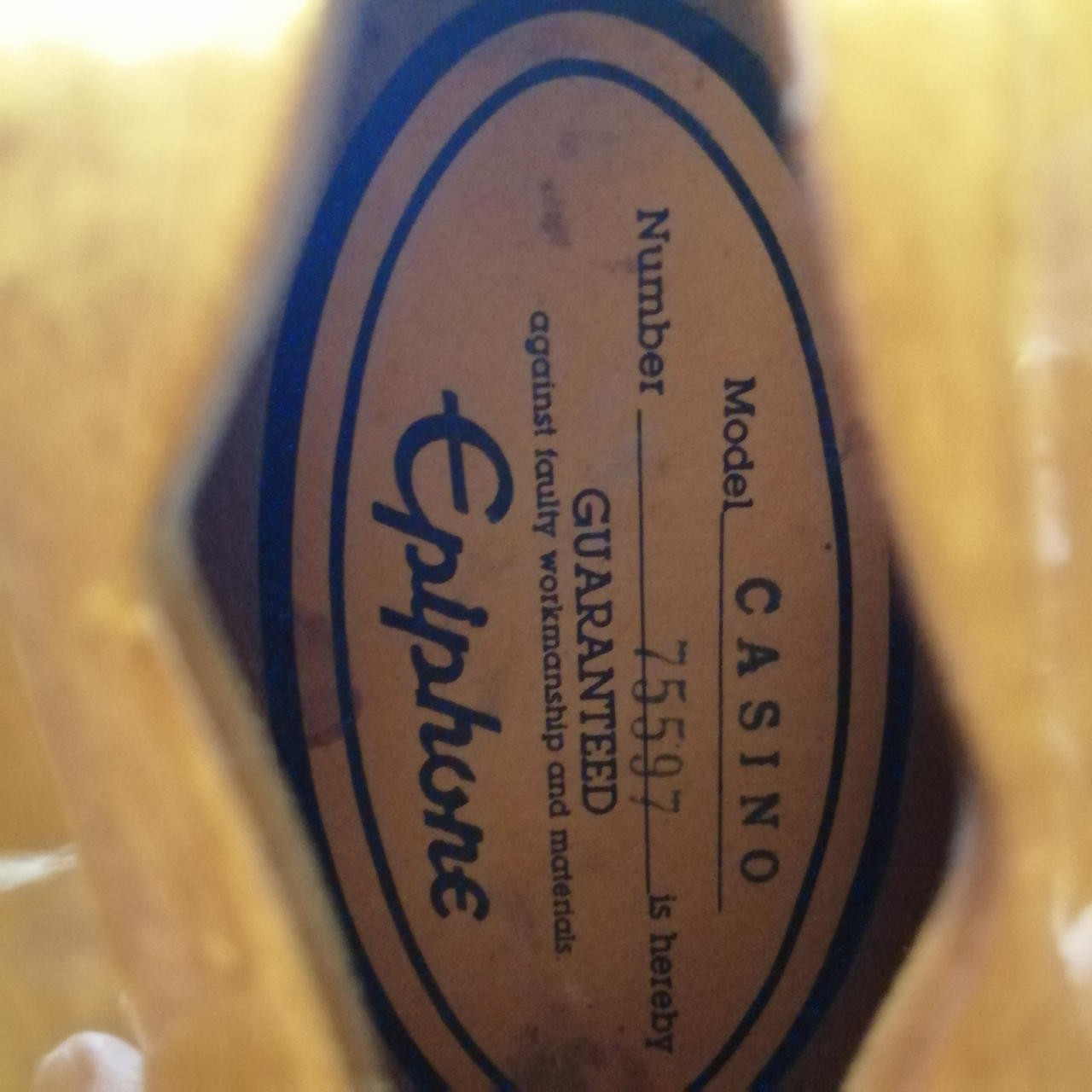 Gold oval Epiphone label with white text, “Number 75597 Casino,” and guarantees against faulty workmanship and materials.