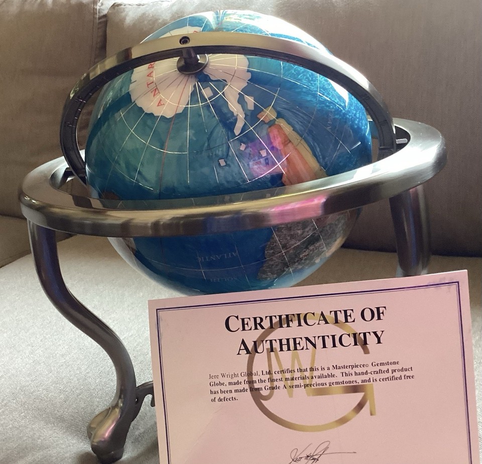 A deep blue gemstone world globe on a gold-plated brass stand — looks like a prop from a Bond villain's lair in the best possible way.
