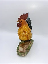 Ceramic rooster statue Standing on grass and wood table decor.