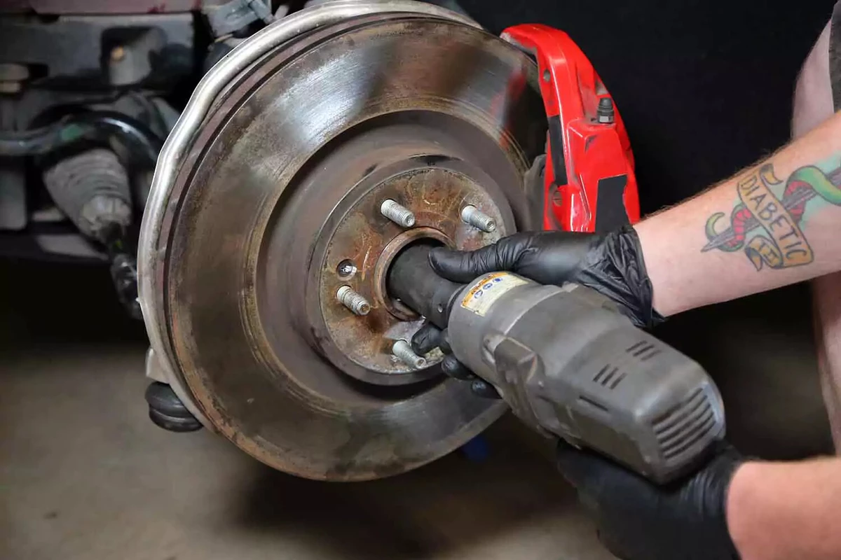 A mechanic uses an impact gun to tighten the axle nut.