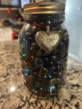 his is a vintage Ball Mason jar filled with assorted glass marbles.