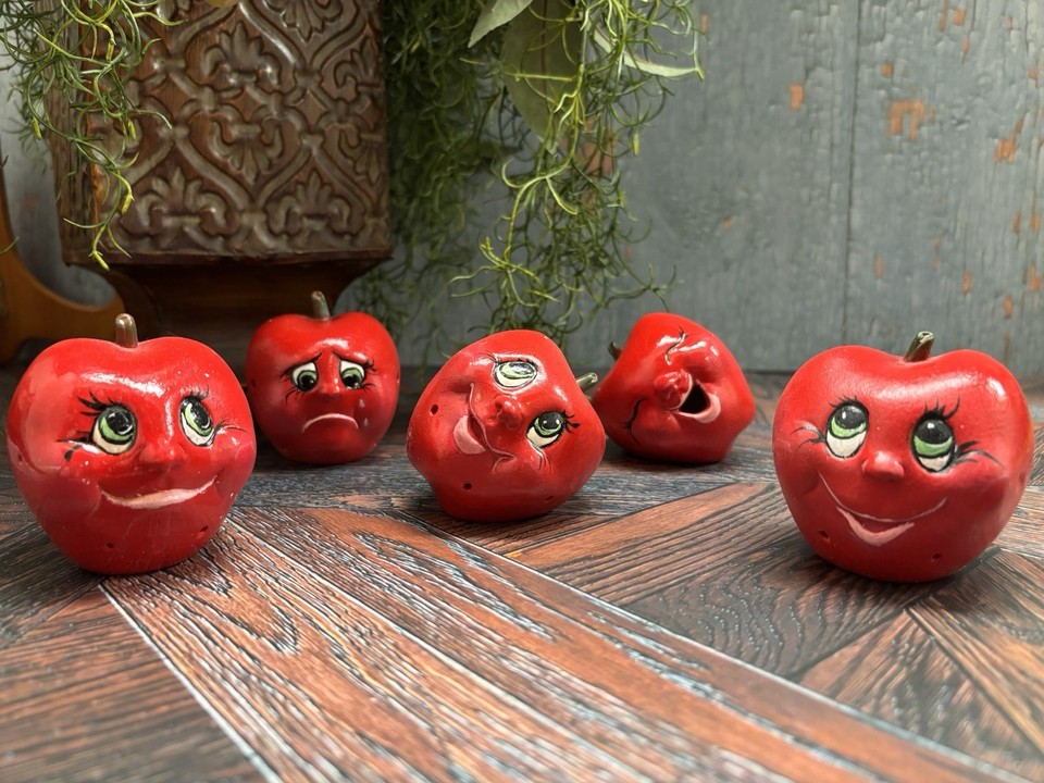 A set of five anthropomorphic apple figurines each pulling a different exaggerated emotional face — peak kitsch absurdity that doubles as instant shelf character.