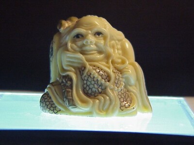 Netsuke - Elder person wrapped in a robe with ear ring