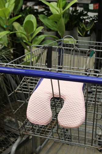 Pink gel polymer and memory foam car seat cushion with textured egg-shaped design, resting on a blue metal shopping cart.